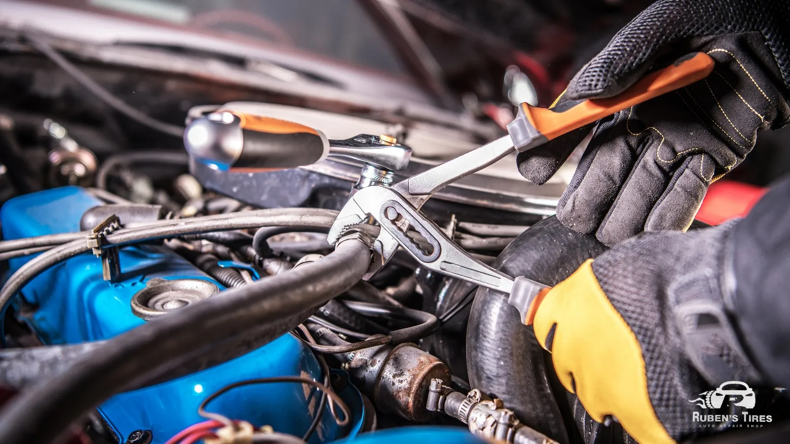 Mechanic tightening engine components for effective car maintenance at Ruben's Tires.