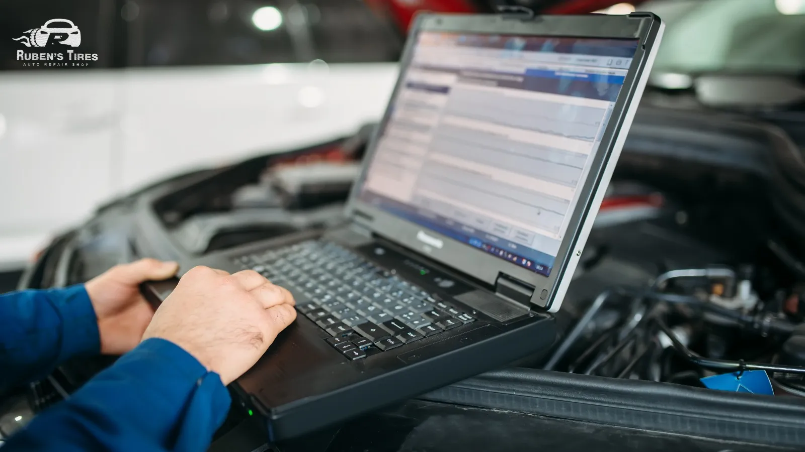 Mechanic using a diagnostic tool to identify vehicle issues during car maintenance at Ruben's Tires.