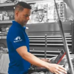 Professional technician working at an Auto Body Shop Central Florida, inspecting a vehicle inside a well-equipped workshop.