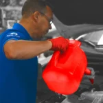 Professional technician wearing red gloves pouring brake fluid during brake repair at a workshop, representing reliable Brake Repair Central Florida services.