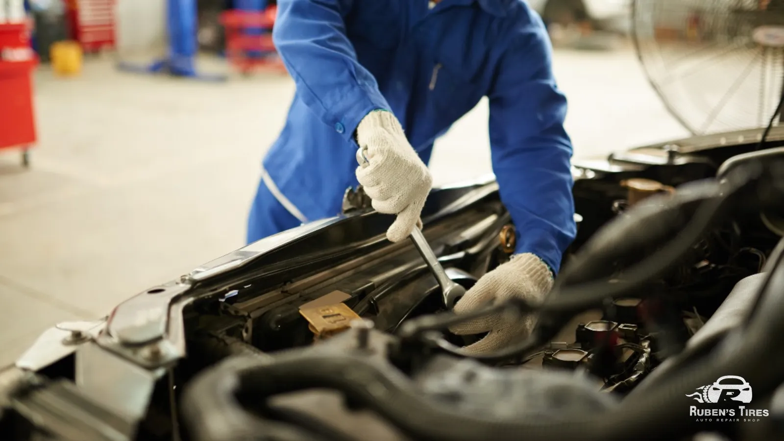 Technician in blue uniform performing engine repairs at Ruben’s Auto Repair.