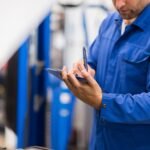 Technician reviewing service information on a digital tablet in a professional garage, reflecting customer support and transparency highlighted in Rubens Tires FAQs.